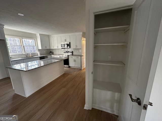 kitchen featuring dark wood-style floors, decorative backsplash, appliances with stainless steel finishes, white cabinets, and a sink