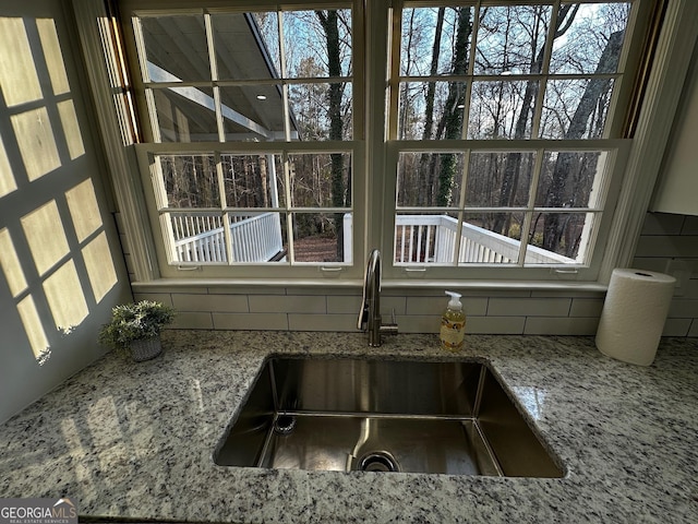 details featuring light stone counters, backsplash, and a sink