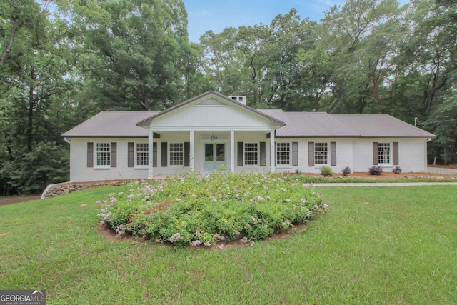 view of front of house with brick siding, metal roof, and a front lawn