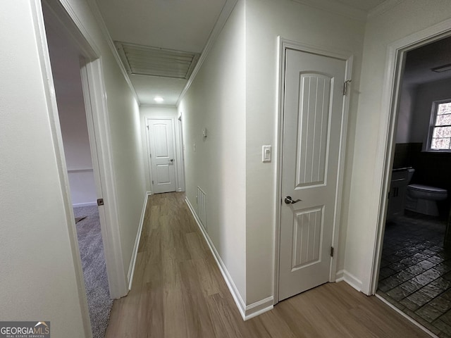 hall with light wood finished floors, baseboards, and crown molding