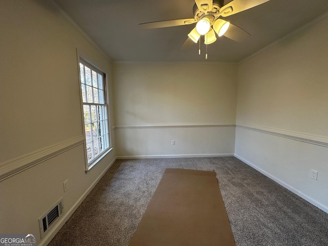 carpeted spare room with baseboards, ceiling fan, visible vents, and crown molding