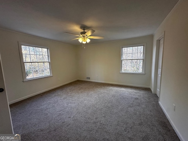 carpeted empty room with a ceiling fan, a wealth of natural light, ornamental molding, and baseboards