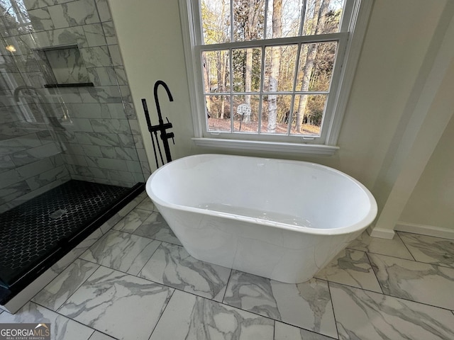 full bathroom with a freestanding bath, marble finish floor, tiled shower, and baseboards