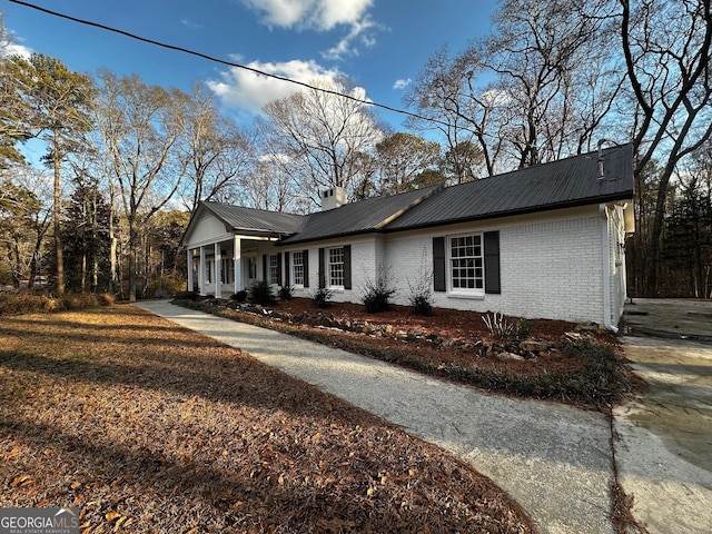 view of home's exterior featuring a chimney, metal roof, and brick siding