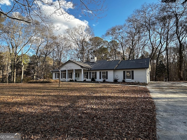 view of front of property with covered porch, a chimney, and brick siding