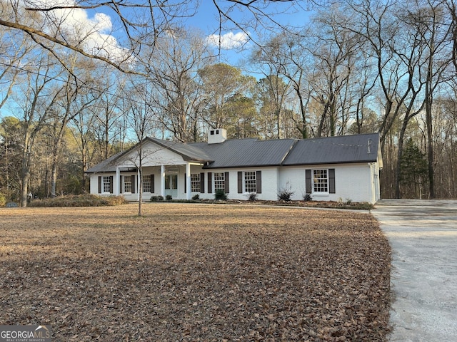 view of front facade with a chimney, a porch, and brick siding