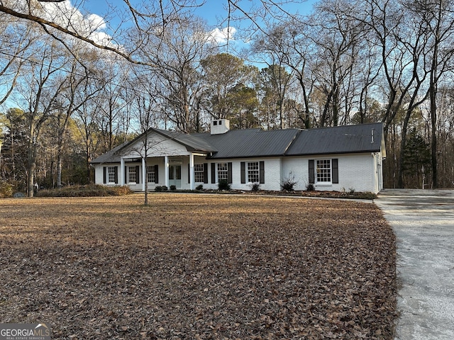 view of front of house featuring covered porch, brick siding, and a chimney