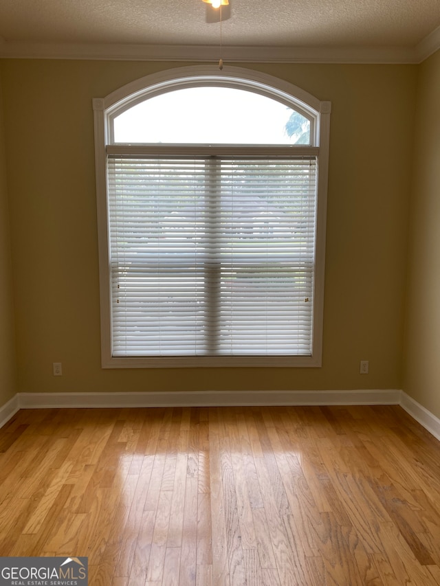 unfurnished room featuring plenty of natural light, ornamental molding, and light hardwood / wood-style flooring