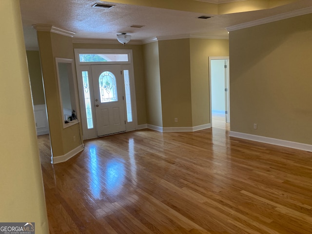 entrance foyer featuring a textured ceiling, light wood-type flooring, and ornamental molding