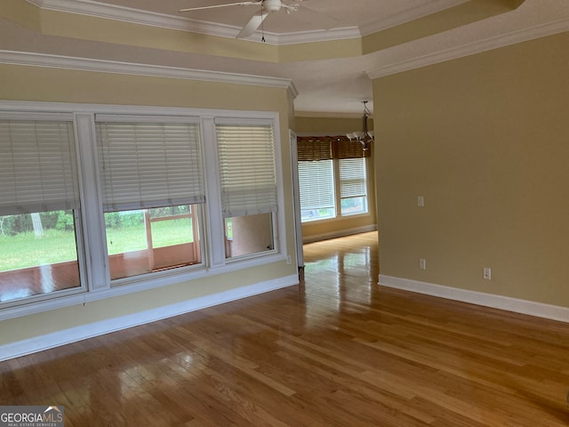 empty room featuring crown molding, plenty of natural light, hardwood / wood-style floors, and ceiling fan with notable chandelier