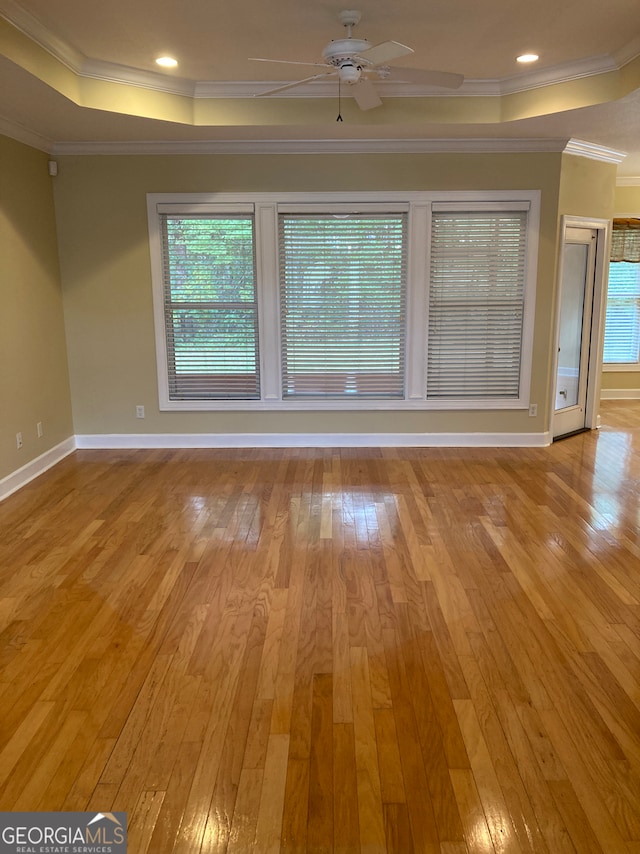 unfurnished room featuring a wealth of natural light, light hardwood / wood-style flooring, ceiling fan, and ornamental molding