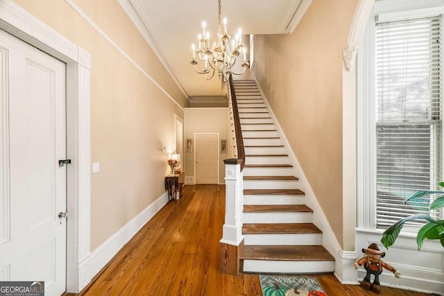 stairs with a notable chandelier, wood-type flooring, and crown molding