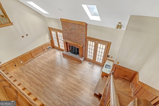 living room with french doors, light hardwood / wood-style floors, and high vaulted ceiling