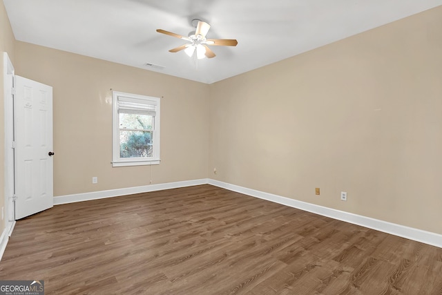 spare room with baseboards, visible vents, and wood finished floors