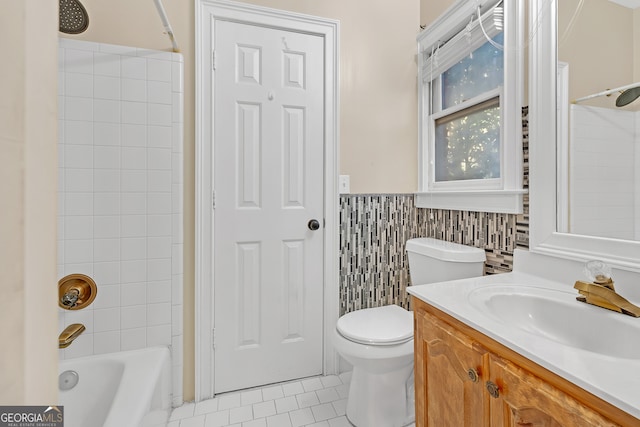 full bathroom with vanity, tile walls, tile patterned flooring, toilet, and tiled shower / bath