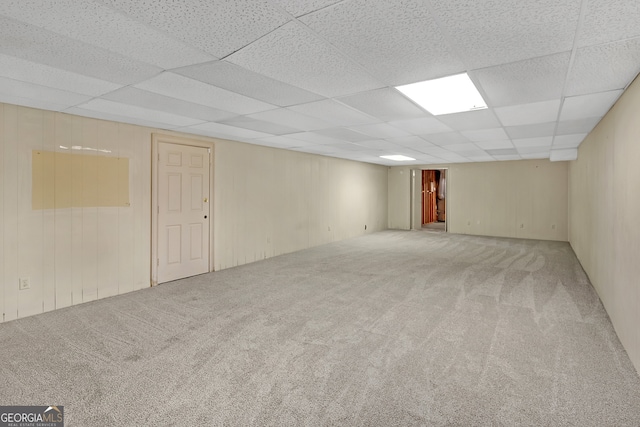 basement featuring a paneled ceiling and carpet