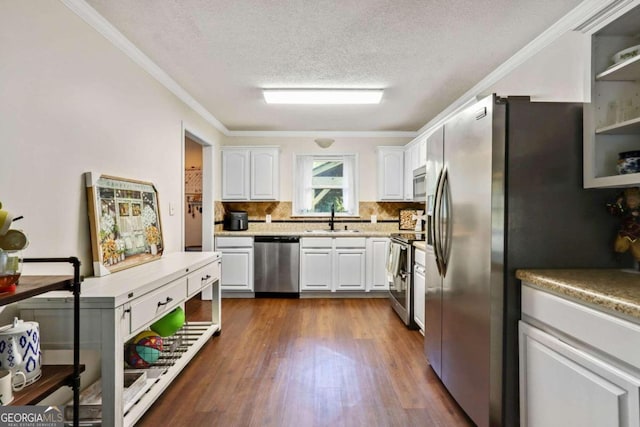 kitchen featuring appliances with stainless steel finishes, dark wood-type flooring, crown molding, sink, and white cabinetry