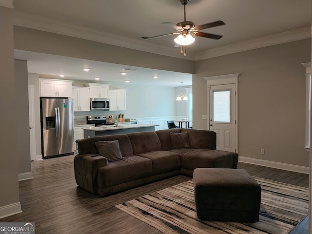 living room featuring ceiling fan with notable chandelier, dark hardwood / wood-style floors, and ornamental molding