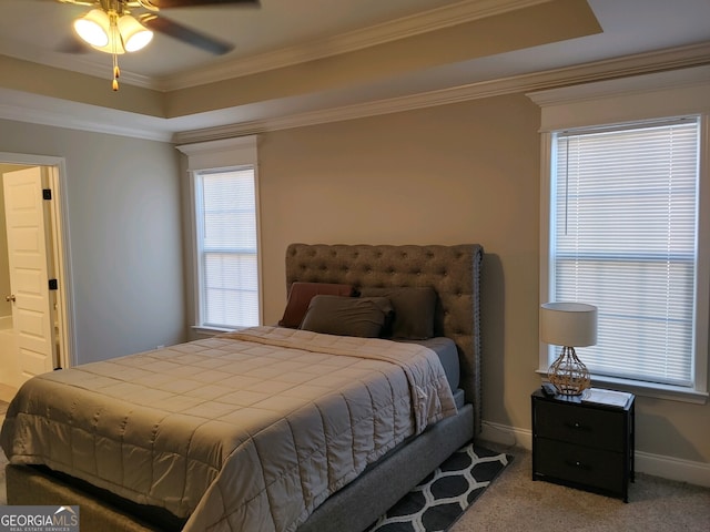 bedroom featuring ensuite bath, ceiling fan, a raised ceiling, crown molding, and carpet floors