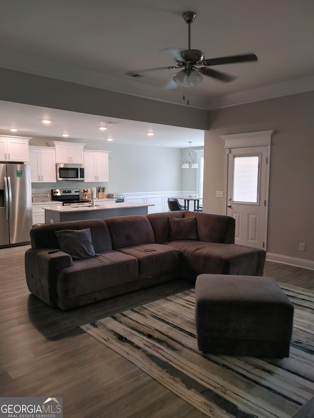 living room with hardwood / wood-style flooring, ceiling fan with notable chandelier, and crown molding