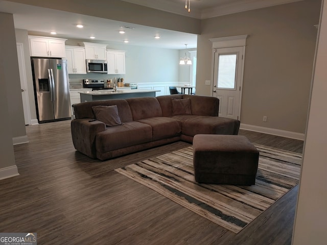 living room with ceiling fan with notable chandelier, dark hardwood / wood-style flooring, and crown molding