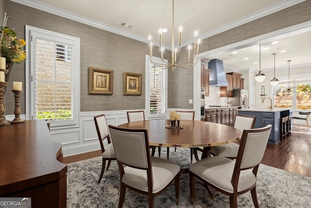 dining area with a chandelier, dark hardwood / wood-style floors, ornamental molding, and sink