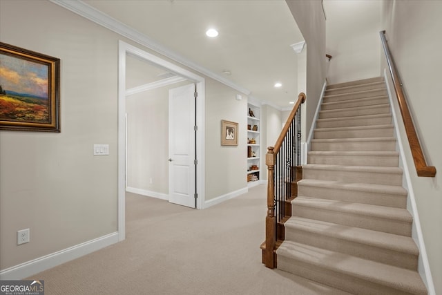 stairway with built in features, carpet floors, and ornamental molding