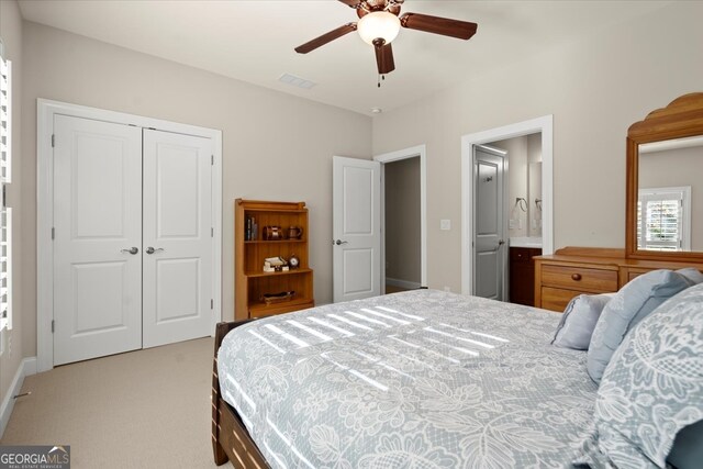 carpeted bedroom featuring ensuite bath, ceiling fan, and a closet