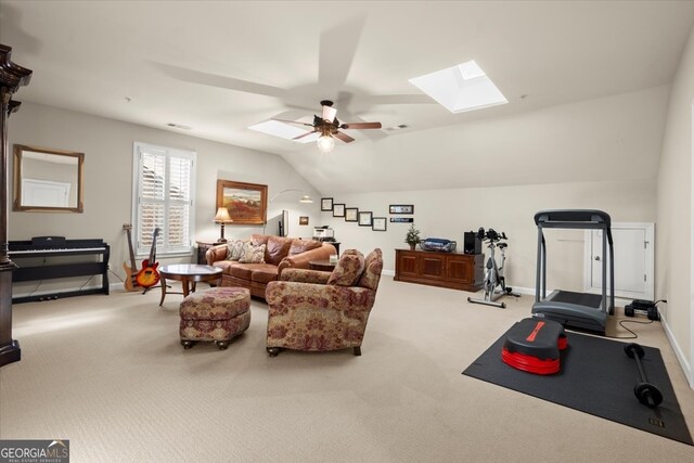 workout room with carpet flooring, ceiling fan, and vaulted ceiling with skylight