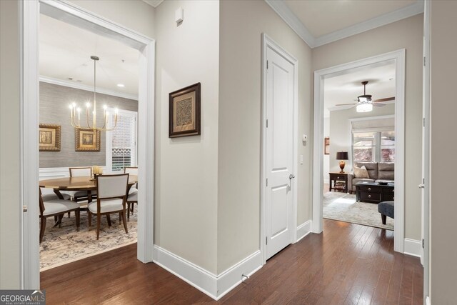 hall featuring crown molding, dark hardwood / wood-style floors, and a notable chandelier