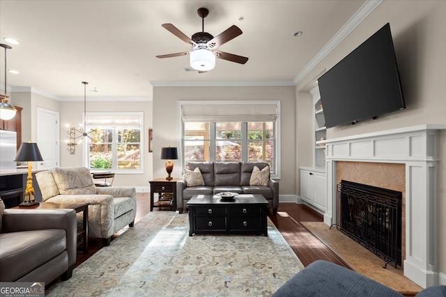 living room with crown molding, ceiling fan with notable chandelier, and hardwood / wood-style flooring