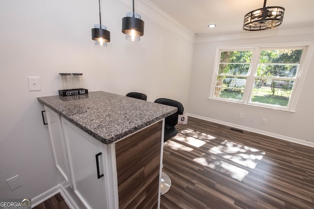 kitchen featuring decorative light fixtures, dark hardwood / wood-style floors, stone countertops, and crown molding