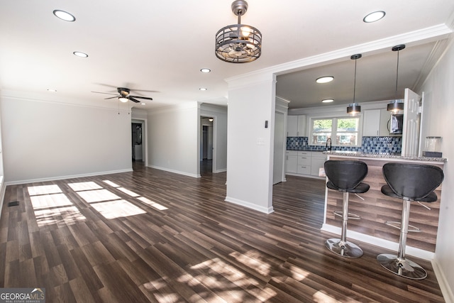 living room with ceiling fan, sink, dark hardwood / wood-style floors, and ornamental molding