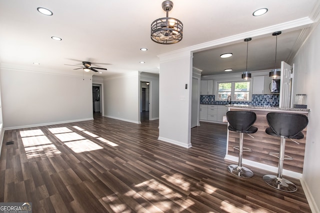 living room featuring dark hardwood / wood-style floors, ceiling fan, and crown molding