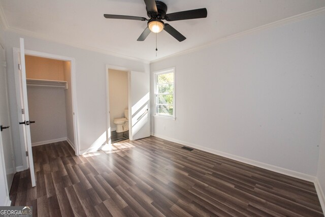 unfurnished bedroom featuring crown molding, ensuite bath, ceiling fan, dark hardwood / wood-style flooring, and a closet