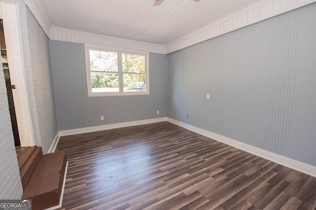 spare room with wooden walls and dark wood-type flooring