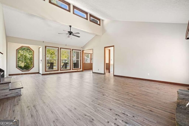 unfurnished living room with a textured ceiling, ceiling fan, wood-type flooring, beam ceiling, and high vaulted ceiling