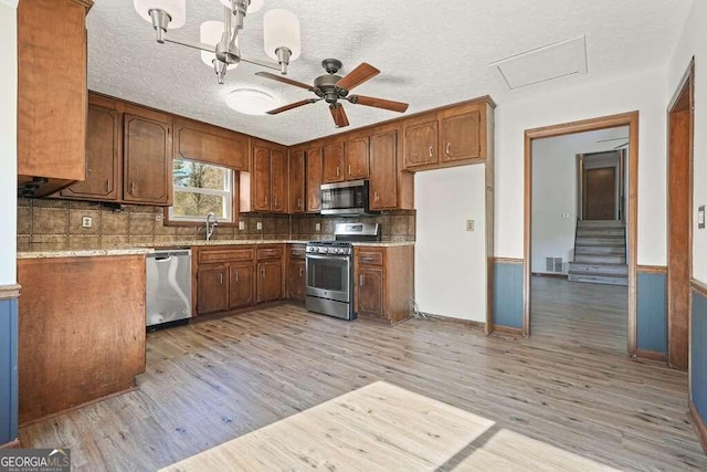 kitchen featuring light hardwood / wood-style flooring, ceiling fan, light stone countertops, a textured ceiling, and stainless steel appliances