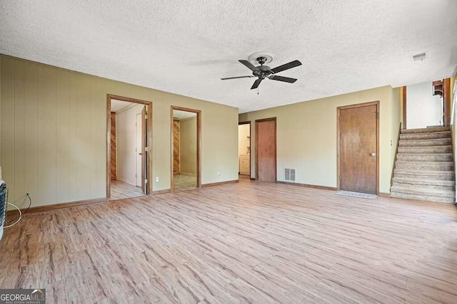 interior space with ceiling fan, a textured ceiling, and light wood-type flooring