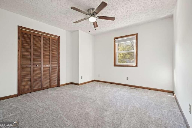 unfurnished bedroom featuring ceiling fan, carpet floors, a textured ceiling, and a closet