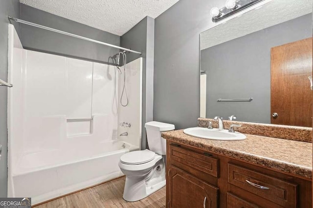 full bathroom with vanity, a textured ceiling, shower / washtub combination, hardwood / wood-style flooring, and toilet