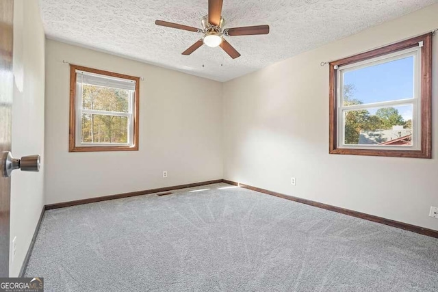 carpeted spare room featuring a textured ceiling and ceiling fan