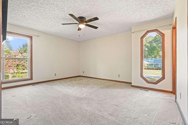 carpeted spare room featuring a textured ceiling and ceiling fan