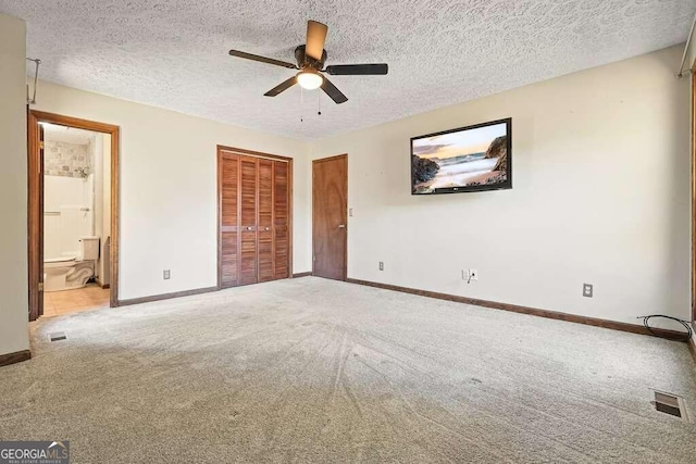 unfurnished bedroom featuring connected bathroom, ceiling fan, carpet, and a textured ceiling