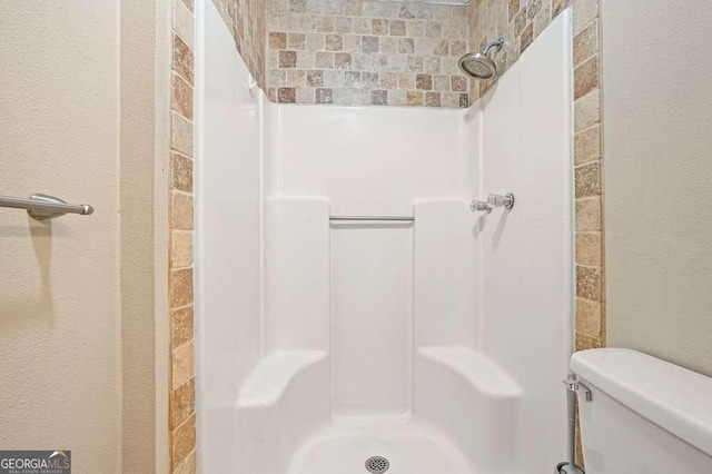 bathroom with tiled shower and toilet