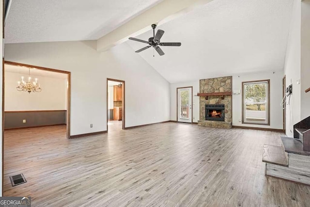 unfurnished living room with ceiling fan with notable chandelier, high vaulted ceiling, light hardwood / wood-style flooring, and a stone fireplace