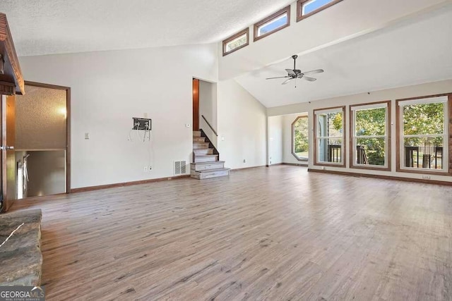 unfurnished living room with hardwood / wood-style flooring, ceiling fan, a textured ceiling, and high vaulted ceiling