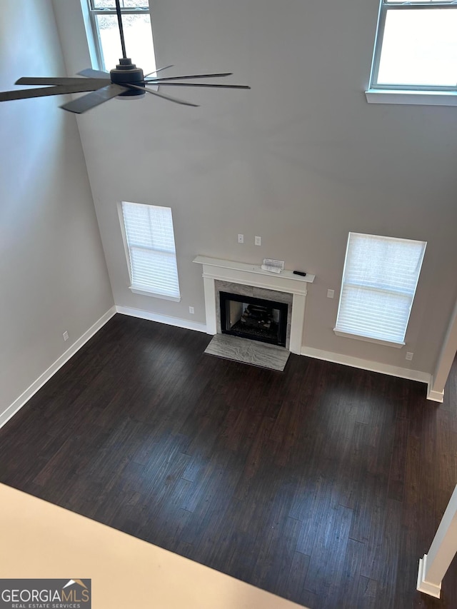 unfurnished living room with ceiling fan, plenty of natural light, and wood-type flooring