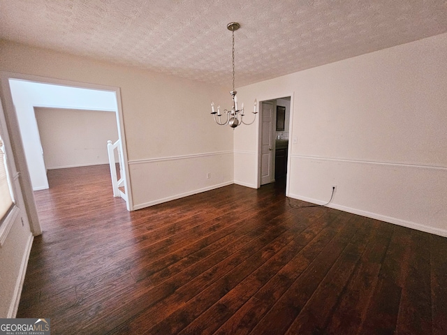 unfurnished dining area with a textured ceiling, a notable chandelier, and dark wood-type flooring