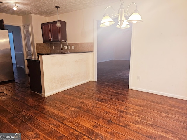 kitchen featuring a textured ceiling, dark brown cabinetry, a notable chandelier, dark hardwood / wood-style floors, and hanging light fixtures